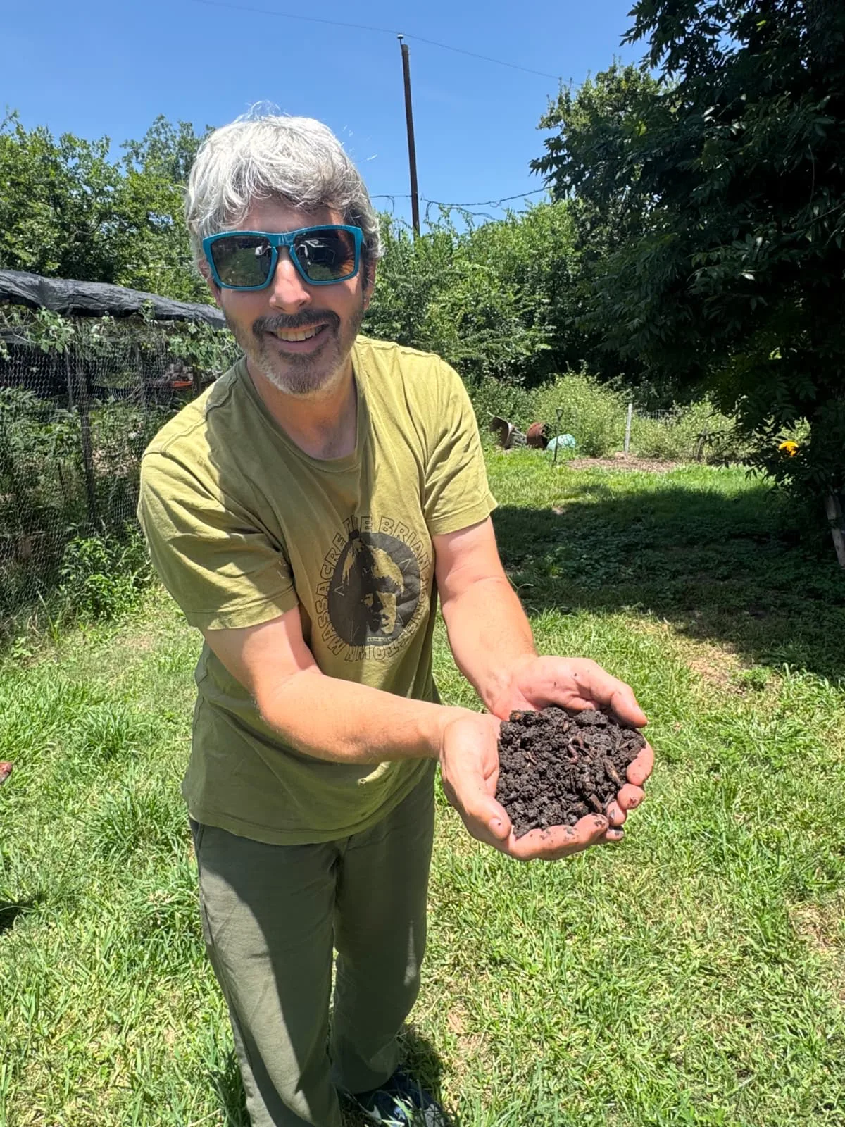 Scott Sheridan, founder of OnFarmCompost, holding a handful of finished compost teeming with worms